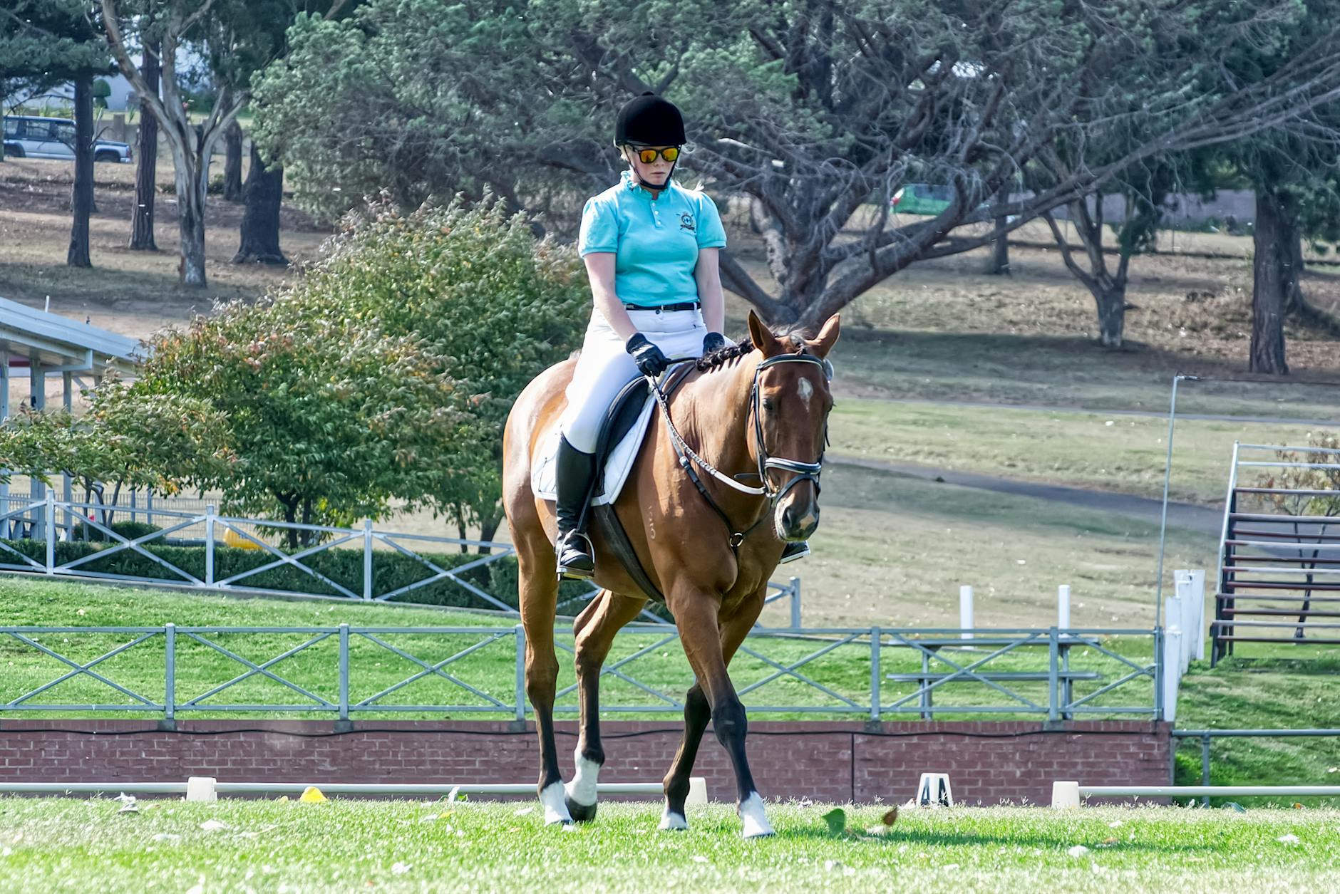 Kobieta w letnim stroju jeździeckim jedzie konno po parku