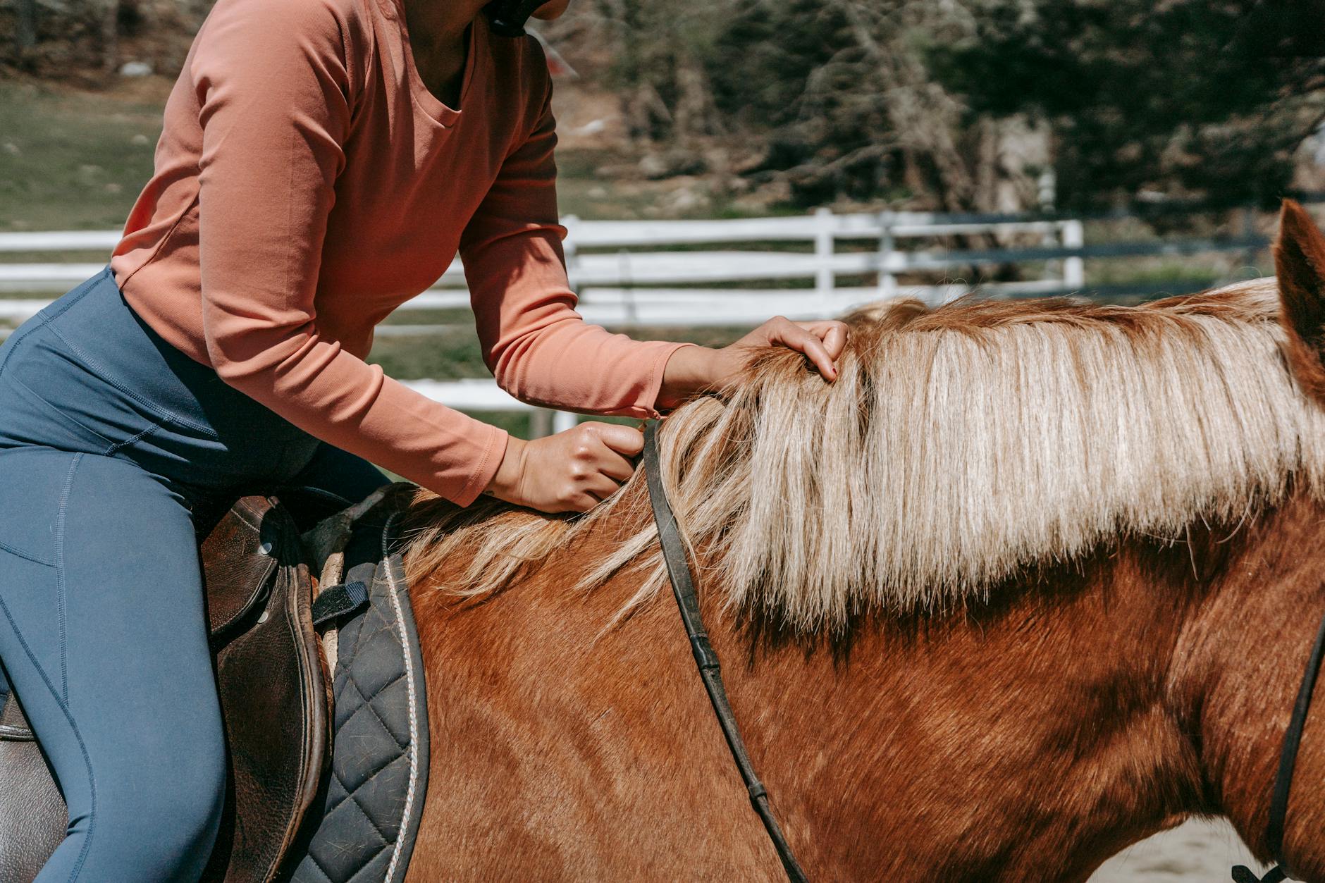 Kobieta w luźnym stroju jedzie konno w słoneczny dzień w terenie