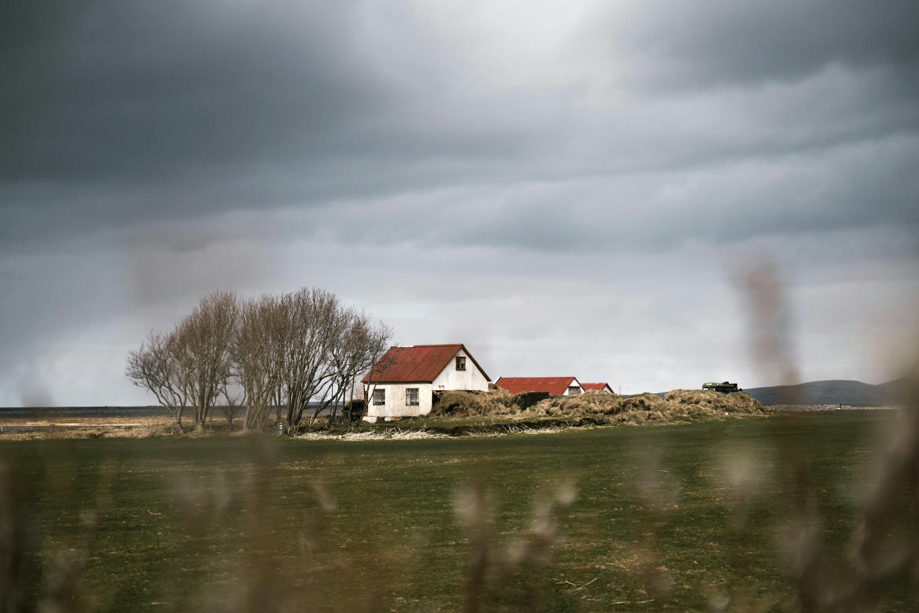 Wiejska zagroda z czerwonymi dachami pod dramatycznym, pochmurnym niebem