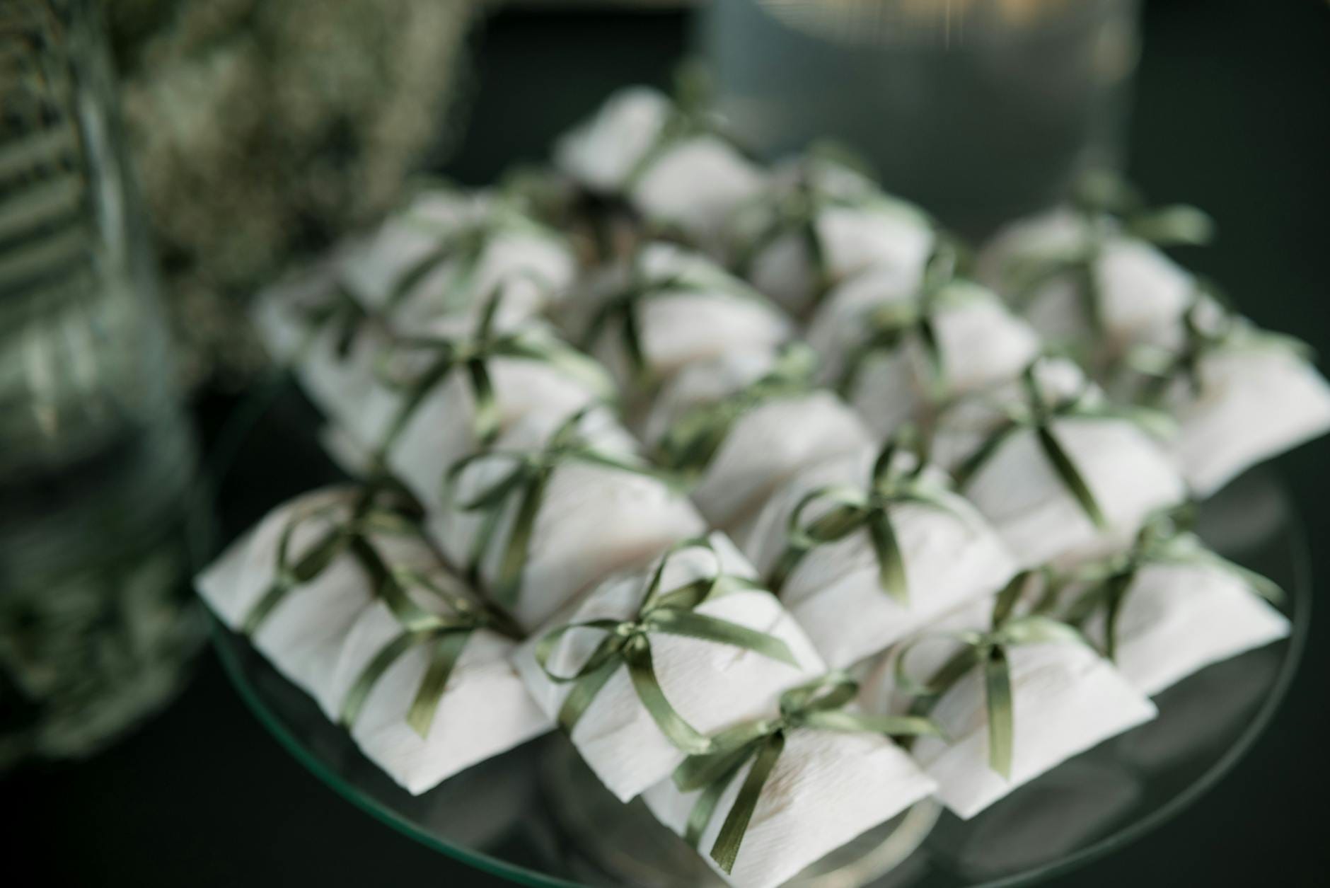 Białe pudełka prezentowe przewiązane zielonymi wstążkami dla pary młodej