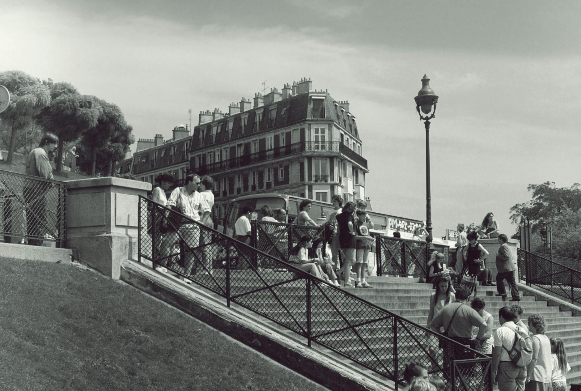 Czarno-białe ujęcie ulicy w Montmartre z przechodniami i starymi kamienicami