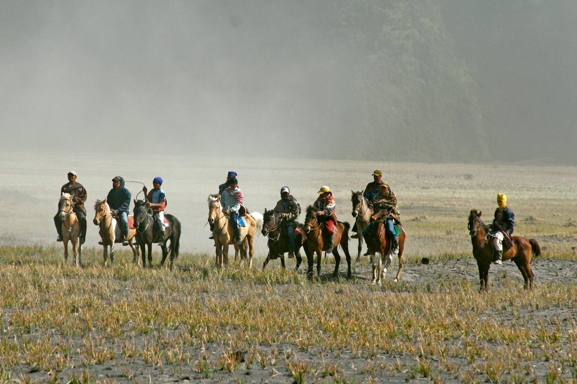 Grupa jeźdźców jedzie konno przez mglisty, otwarty teren