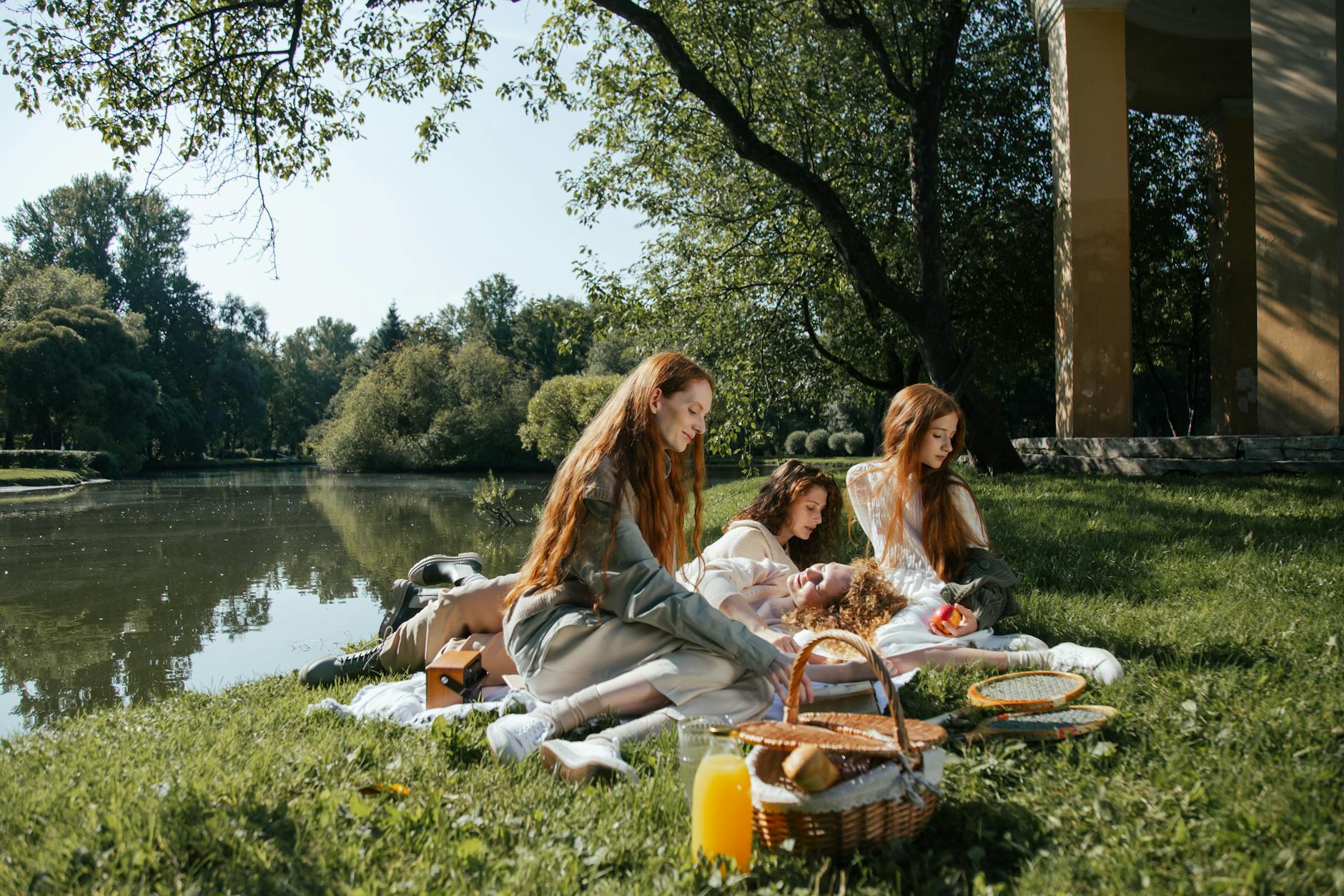Cztery kobiety na kocu podczas rodzinnego pikniku nad stawem