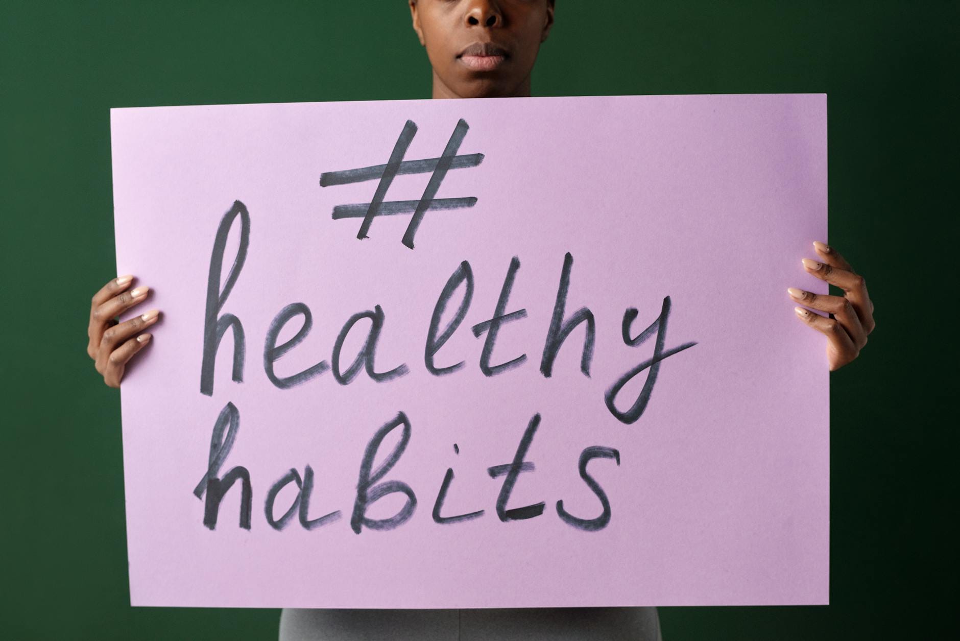Osoba trzymająca kartkę z napisem healthyhabits na tle jasnej ściany