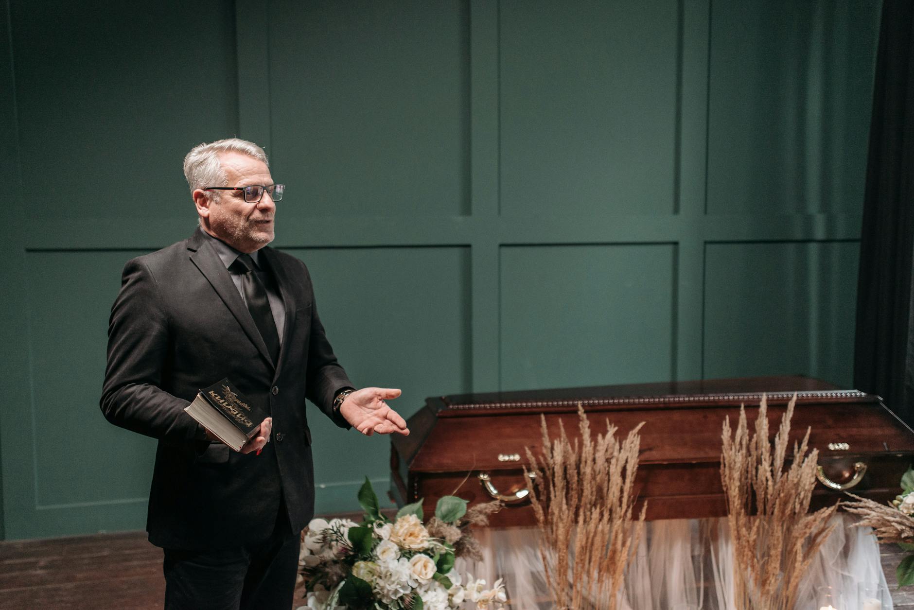Pastor przemawia przy drewnianej trumnie z kwiatami podczas pogrzebu Pastor przemawia przy drewnianej trumnie z kwiatami podczas pogrzebu